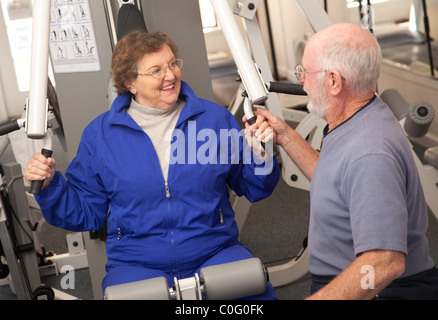 Senior Adulto Giovane lavorando insieme in palestra con varie macchine per il fitness. Foto Stock