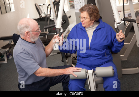 Senior Adulto Giovane lavorando insieme in palestra con varie macchine per il fitness. Foto Stock