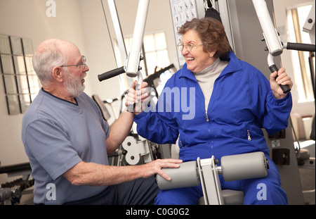 Senior Adulto Giovane lavorando insieme in palestra con varie macchine per il fitness. Foto Stock