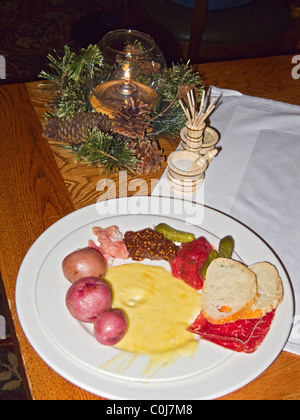 Piatto di formaggio raclette e di verdure a pranzo con caminetto a cena, Deer Valley, Utah. Foto Stock