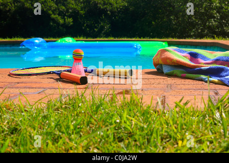 Piscina con il blu e il verde materassini gonfiabili e un giardino badminton set. Foto Stock