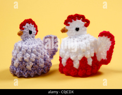 Coppia di carino in maglia di gallina uova di Pasqua di scaldini su sfondo giallo. Foto Stock