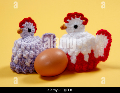 Coppia di carino in maglia di gallina uova di Pasqua di scaldini su sfondo giallo. Foto Stock
