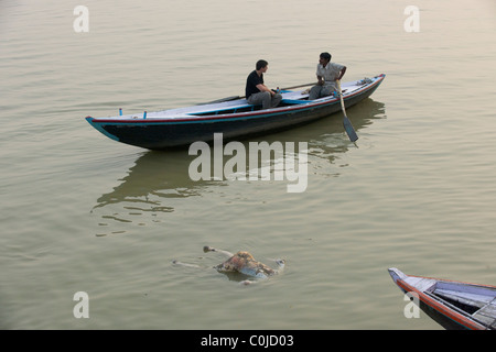 Il corpo di un morto prgnant donna passato flottante un turista occidentale in una barca a remi, sul fiume Gange, Varanasi, Uttar Pradesh, India Foto Stock