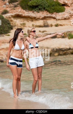 Due donna attraente in bikini di camminare sulla spiaggia Foto Stock