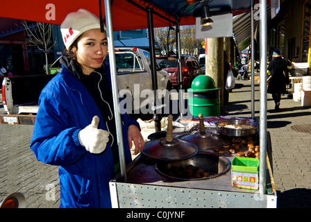 Giovane donna vendita di Castagne Pistacchi dal carrello in ingresso al Granville Island Mercato Pubblico di Vancouver Foto Stock