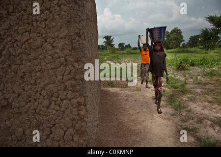 Le ragazze portano a casa di acqua da un pozzo in Safo, Mali, Africa occidentale. Foto Stock