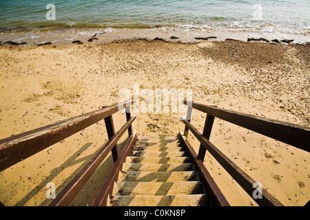 Scale di legno che conducono in basso verso una spiaggia di sabbia con la bassa marea - 2 Foto Stock