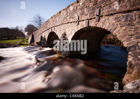 Esposizione lento che mostra il flusso del fiume Dart sotto il ponte a ponte post, dartmoor Foto Stock