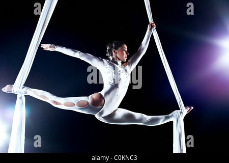 Giovane donna ginnasta. Su sfondo nero con effetto flash. Foto Stock