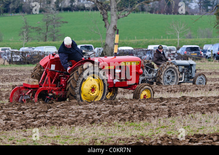 Gli agricoltori che utilizzano i trattori d'epoca per arare un campo Foto Stock