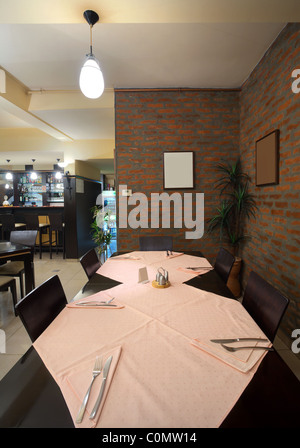 Tavoli e sedie e un muro di mattoni, interni di un ristorante. Foto Stock