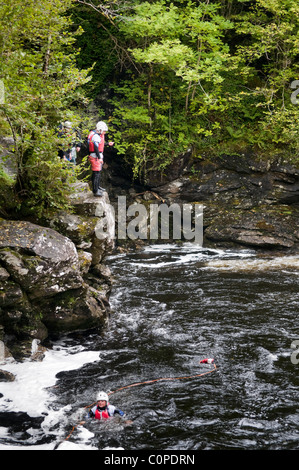 Gorge walking, noto anche come canyoning a cadute di Falloch appena fuori la A82 a poche miglia a sud di Crianlarich, Scozia Foto Stock