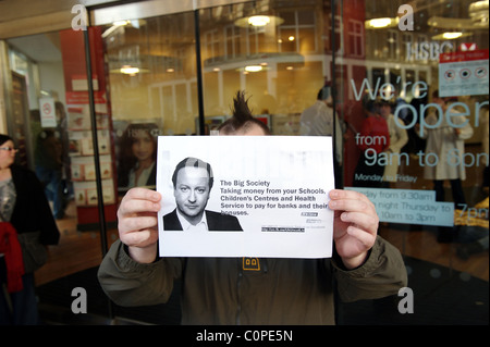 Regno Unito intonso attivista tenendo in mano un poster al di fuori di un ramo di HSBC che è stata chiusa da manifestanti di Liverpool, Febbraio 2011 Foto Stock