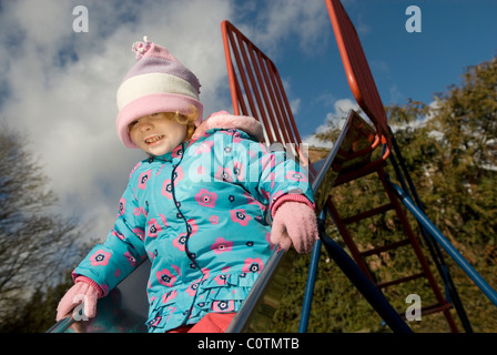 Femmina in età prescolare bambino lo scorrimento verso il basso il parco giochi slitta Foto Stock