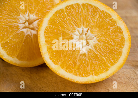 Close up sulle due metà di un taglio di colore arancione su un tagliere di legno Foto Stock