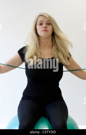 Ragazza adolescente facendo pilates utilizzando una palla e esercizi di stretching Foto Stock