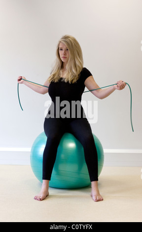 Ragazza adolescente facendo pilates utilizzando una palla e esercizi di stretching Foto Stock