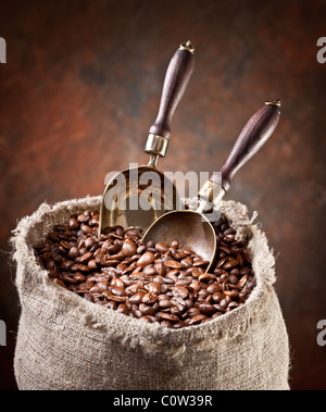 Sacco di chicchi di caffè e scoop. Su uno sfondo scuro. Foto Stock