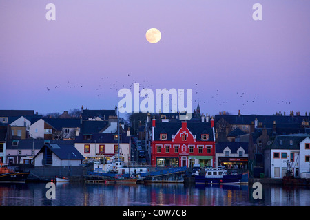 Porto di Stornoway con la Luna Piena al tramonto. Foto Stock