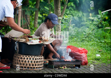 Una strada fornello sate, in Bali, Indonesia, griglie bastoncini di pollo e maiale per i viaggiatori affamati presso il Tempio Besakih. Foto Stock