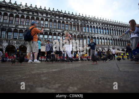 Turisti in Piazza San Marco piccioni alimentazione Venezia Italia Foto Stock