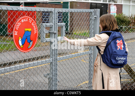 Essere Cool a scuola a piedi segno su un cancello di scuola giovane ragazza andare a scuola a piedi Inghilterra REGNO UNITO Foto Stock