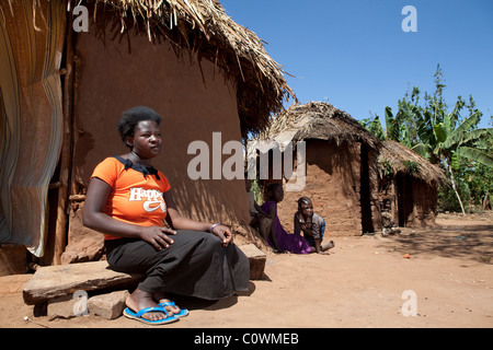 Una giovane donna siede al di fuori di casa sua - Jinja Distric, Uganda Africa Orientale. Foto Stock