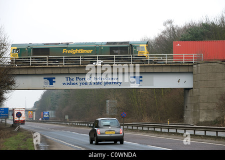 Treno merci che attraversa la A14 trunk road, porto di Felixstowe, Suffolk, Regno Unito. Foto Stock