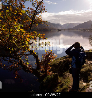 Tourist ammirando le riflessioni nelle calme acque del lago Ullswater sul modo di Ullswater, Glenridding, Lake District, Cumbria, England, Regno Unito Foto Stock