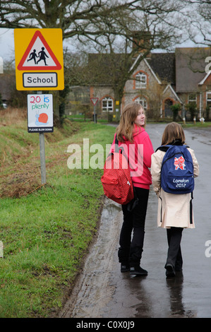 Scolari andare a scuola a piedi lungo una strada di campagna senza marciapiede o la passerella Hampshire England Regno Unito Foto Stock