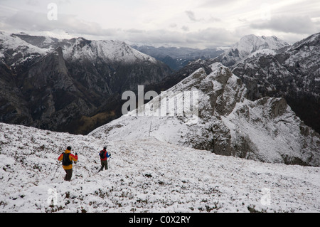 Due escursionisti a piedi attraverso la coperta di neve montagne di Ponga, Asturias, Spagna. Foto Stock