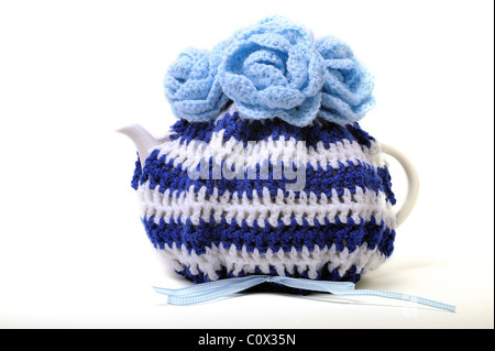 Teacozy fatti a mano in blu e bianco con fiori sul più alto di tutti è con la maglia di lana e ha un gingham blu e nastro bianco Foto Stock