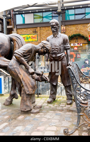 Camden Town o bloccare o cavalli o maneggio mercato , Londra , scultura o statua del fabbro o maniscalco a ferro di cavallo di fissaggio su zoccolo Foto Stock