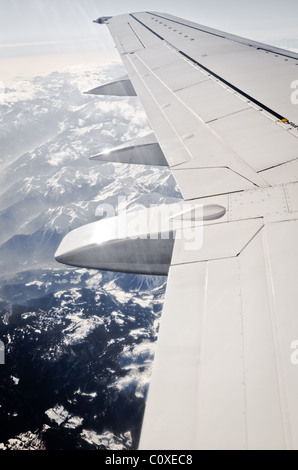 Ala di aeroplano volare al di sopra delle montagne innevate Foto Stock