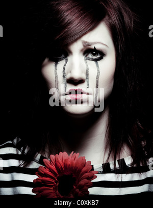 Un triste femmina clown mime con un fiore rosso Foto Stock