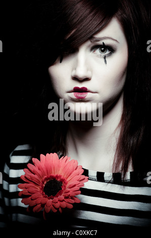 Un triste femmina clown mime con un fiore rosso Foto Stock