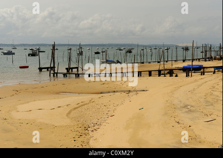 Shore davanti con poli mostra oyster letti di raccolta in Cap Ferret, baia di Arcachon, Dipartimento della Gironde, Francia Foto Stock