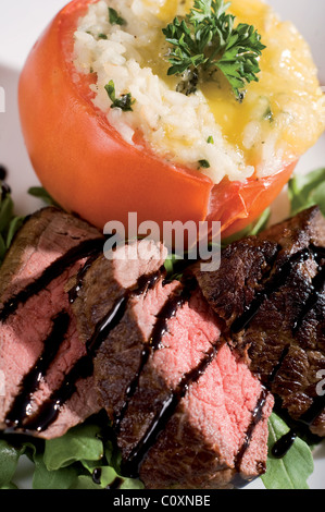 Pan fried Lakeland di manzo con formaggio blu risotto farcito di pomodoro di manzo con un razzo e smalto basamic insalata. Foto Stock