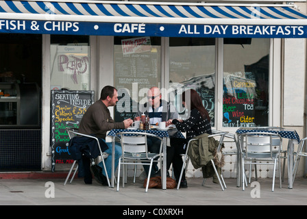 Persone mangiare a un tavolo in un cafe' sul marciapiede Foto Stock