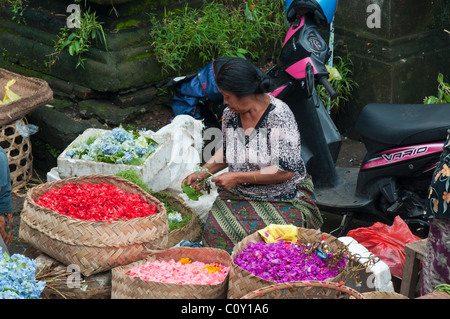 Donna vendita di petali di fiori per la realizzazione di offerte nel mercato in Ubud Bali Indonesia Foto Stock