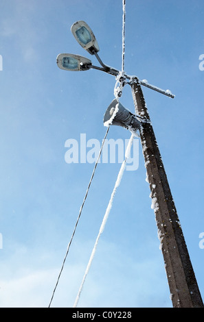 Altoparlante, lampade e cavi elettrici isolati su blu cielo invernale coperto di neve Foto Stock