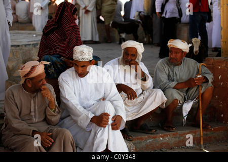 Gli uomini discutere di affari presso il mercato del bestiame in Nizwa, Oman. Foto Stock