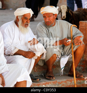 Gli uomini discutere di affari presso il mercato del bestiame in Nizwa, Oman. Foto Stock