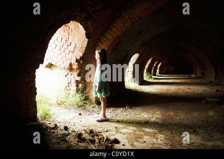 La ragazza si erge in arcate di mattoni abbandonati forno Foto Stock