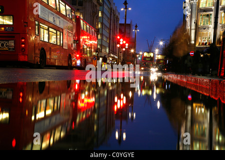 Visualizza in basso un wet Oxford Street per gli autobus in attesa di attraversare Oxford Circus, London, Regno Unito Foto Stock