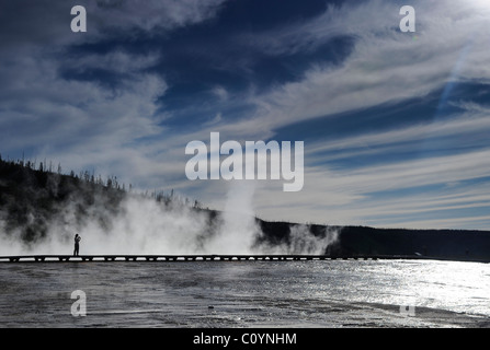 Persona che stava su una passerella su uno di Yellowstone's piscine termali con vapore in aumento in imbuti termico dalla superficie dell'acqua. Foto Stock