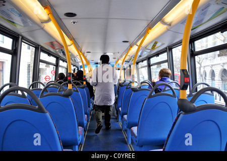 All'interno di Londra autobus a due piani piano superiore interno vista posteriore dei passeggeri piano superiore uno in piedi per uscire altri posti a sedere vista della fermata dell'autobus segno Inghilterra UK Foto Stock