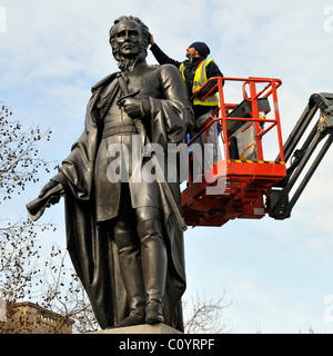 Pulitori su un cherry picker piattaforma di accesso pulizia statua in bronzo Foto Stock