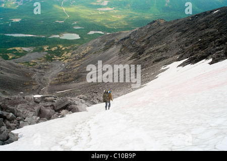 L'uomo in montagna a piedi sulla neve in montagna e andare verso il basso lontano nella valle. Russia, Khibins massiccia, penisola di Kola Foto Stock